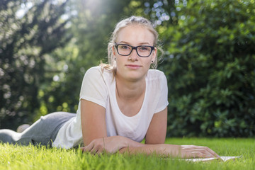 Ein junges Mädchen liegt im Gras und lächelt