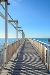 Seaside bridge with kissing points and benches on Black Sea, blue clear water and sunny day sky