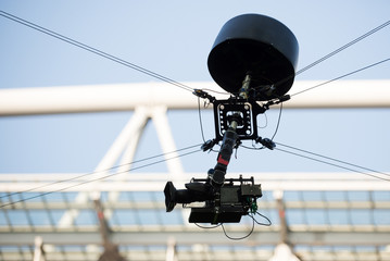 A television camera hangs on cables for football or a concert