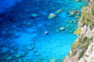Young woman swimming in transparent Ionian Sea near boat. View from Angelokastro on Corfu island, Greece.