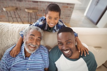Obraz premium Smiling multi-generation family sitting together on sofa