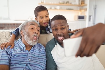 Smiling multi-generation family taking selfie from mobile phone