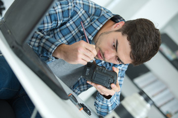 young handsome technician examining and repairing dslr camera