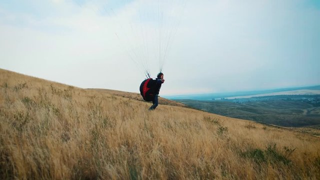 hang glider flying over a field. The wing of the paraglider lies on the ground in the steppe. Soon they will take off. Feeling of freedom and a sense of flying. The beginning of adventure. Paraplane.