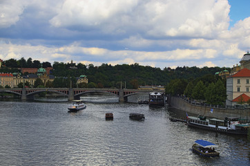 Fototapeta na wymiar View of Manes Bridge and river Vltava. Two boats are rolling tourists. Prague, The Czech Republic