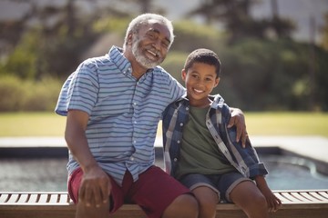 Smiling grandfather and grandson sitting together on bench