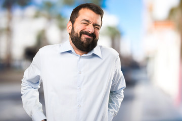 Handsome man with beard with back pain on unfocused background