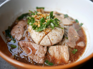 thai noddle of jumbo pork ball, pig liver, pork slide and vegetable on wooden table, hot noodle with blood pink for soup, in Thailand call Boat Noddle.