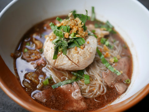 thai noddle of jumbo pork ball, pig liver, pork slide and vegetable on wooden table, hot noodle with blood pink for soup, in Thailand call Boat Noddle.