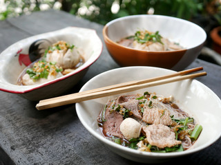 thai noddle of jumbo pork ball, pig liver, pork slide and vegetable on wooden table, hot noodle with blood pink for soup, in Thailand call Boat Noddle.