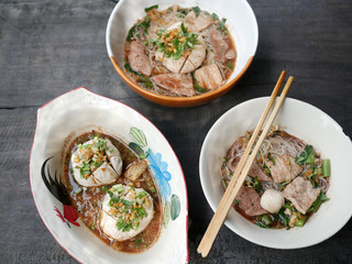 thai noddle of jumbo pork ball, pig liver, pork slide and vegetable on wooden table, hot noodle with blood pink for soup, in Thailand call Boat Noddle.