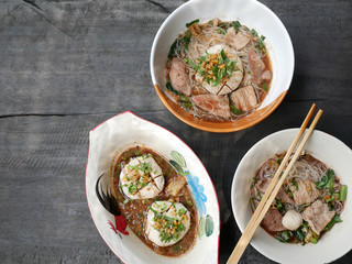 thai noddle of jumbo pork ball, pig liver, pork slide and vegetable on wooden table, hot noodle with blood pink for soup, in Thailand call Boat Noddle.