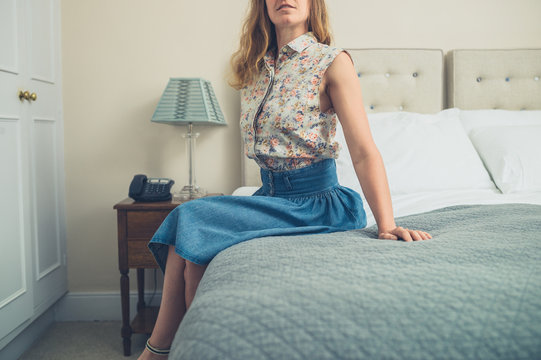 Young woman sitting on bed in hotel room