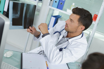 Naklejka na ściany i meble male radiologist looking at x-ray with patient