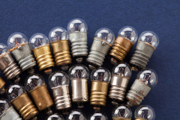 Light bulbs set on blue paper background. Colorful gold bronze and silver vintage lamps. Macro view shallow depth field.