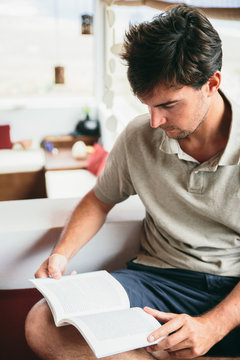 Man reads a book on his knee indoor at home