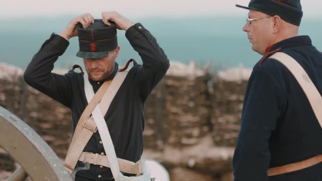 French soldier corrects the cap while the other shoots the gun