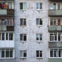 Fototapeta na wymiar Windows and balconies of the old brick apartment building in Russia