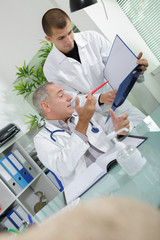 Obraz premium portrait of male doctor and his assistant holding a folder