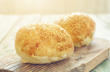 homemade buns for burger on wood cutting board. sunlight on background 