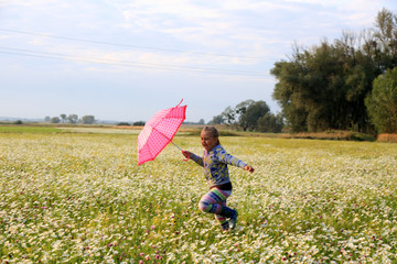 Śliczna dziewczynka biega z parasolką wśród polnych kwiatów. - obrazy, fototapety, plakaty