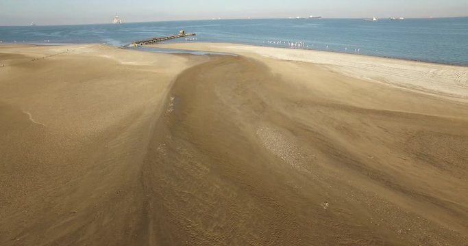 Aerial view drone video of Pelican Point Lodge and Paratus lighthouse on sand beach peninsula, shipwreck and lagoon with ocean background with ships at Namibia's Atlantic west coast