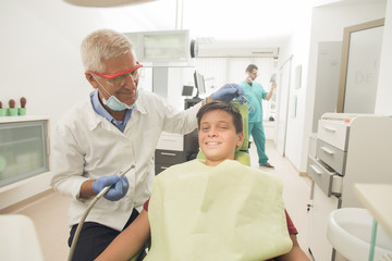 Obraz premium oy with perfect teeth at the dentist doing check up with the clinic at the background - oral hygiene health care concept