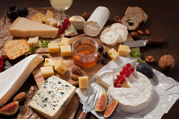 Variety of different cheese with wine, fruits and nuts. Camembert, goat cheese, roquefort, gorgonzolla, gauda, parmesan, emmental
