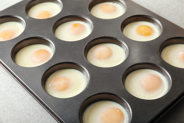 Muffin tin with eggs on table, closeup