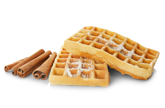 Tasty homemade waffles with sugar powder and cinnamon sticks on white background