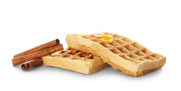 Tasty homemade waffles with honey and cinnamon sticks on white background