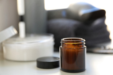 Glass jar with cosmetic on table