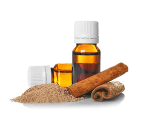 Glass bottles with essential cinnamon oil, powder and sticks on white background