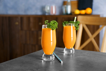 Glasses with fresh carrot juice and parsley on table