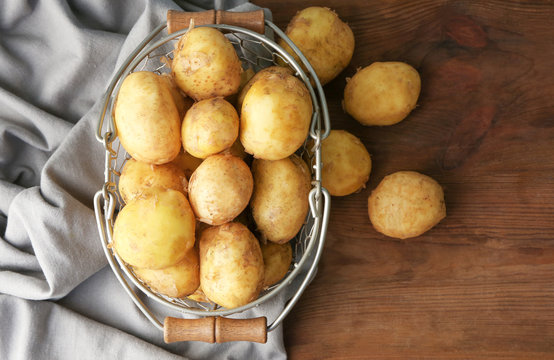 Metal basket with young potatoes on wooden table