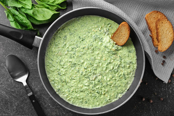 Frying pan with tasty spinach sauce on table