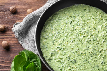 Frying pan with tasty spinach sauce on table