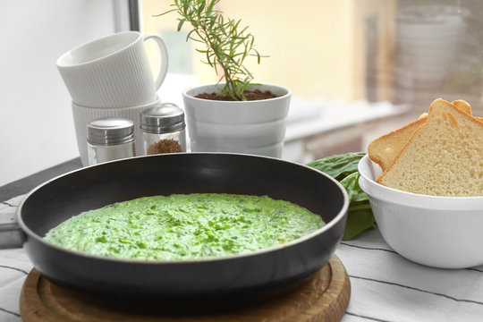 Frying pan with tasty spinach sauce on table