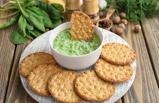 Bowl with tasty spinach sauce and cookies on table
