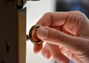 Hand of a woman turning a key on a door