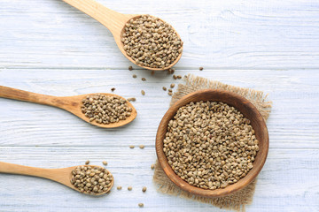 Bowl and spoons with hemp seeds on wooden background