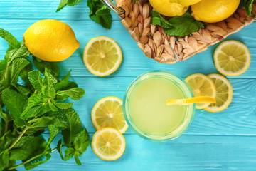 Glass of lemon juice, fresh lemons and mint on blue table