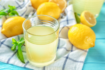 Composition with glass of lemon juice and fresh lemons on table