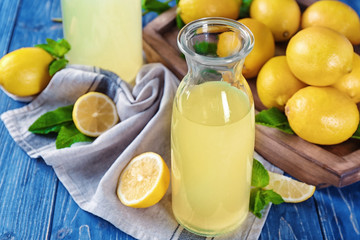 Composition with bottle of lemon juice and fresh lemons on table