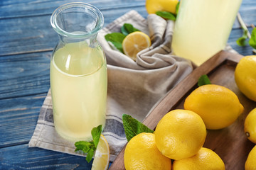 Composition with bottle of lemon juice and fresh lemons on table