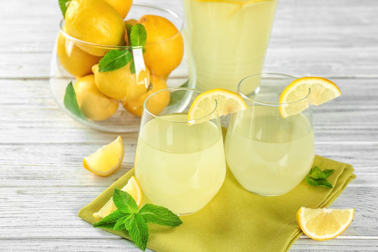 Two glasses of lemon juice and fresh lemons on table