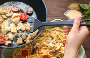 Woman cooking turkey tetrazzini in kitchen