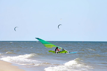 Windserfer learns beach start element with sail at sea ocean