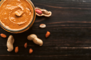 peanut butter on a table in a glass jar with peanuts around