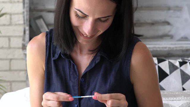 Picture of happy young woman looking at positive pregnancy test.